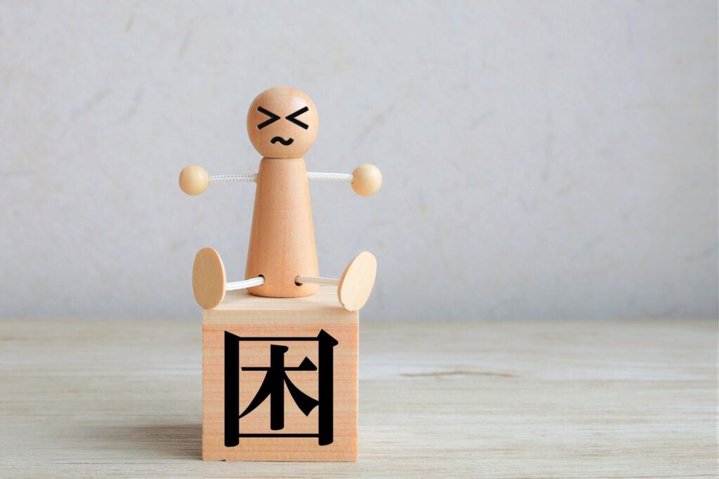 「困」と書かれた木製ブロックの上で困った表情をした人形を配置したアイキャッチ画像